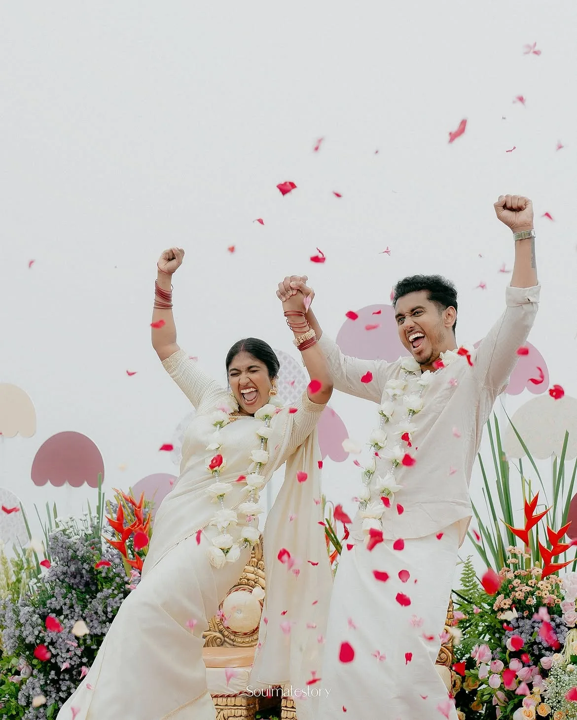 A newly married couple celebrating under falling rose petals