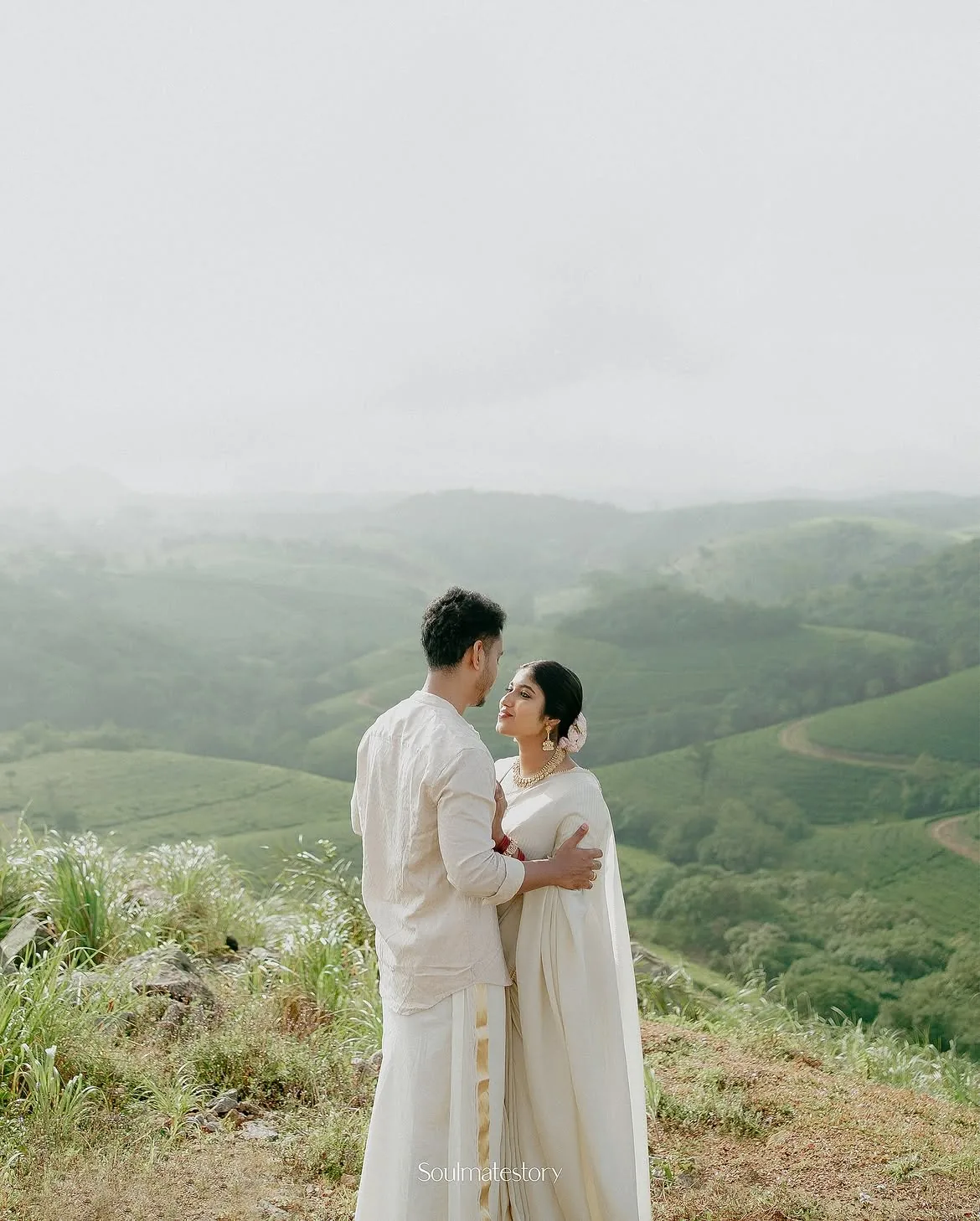 A couple embracing among misty green hills